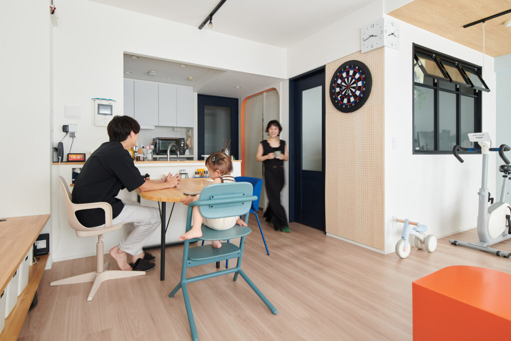 キッチンとダイニング、家族3人が集まるシーン。奥にはバイクと子ども用乗り物