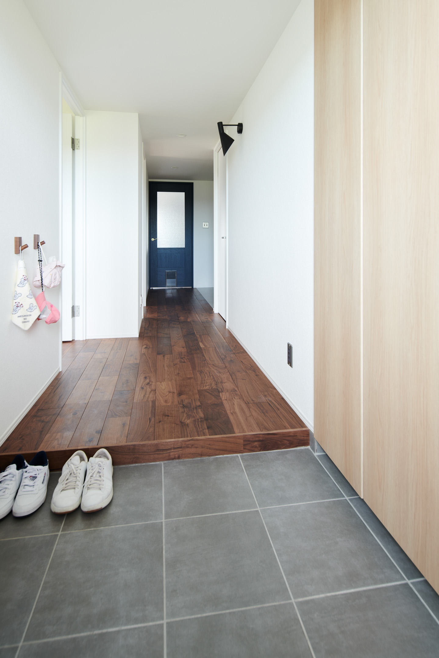 廊下の床材もウォルナット。新設した玄関のシューズボックスは他とは違い明るめの建具を採用した。プッシュ式で使っている部分の変色が目立たないようにという配慮から。